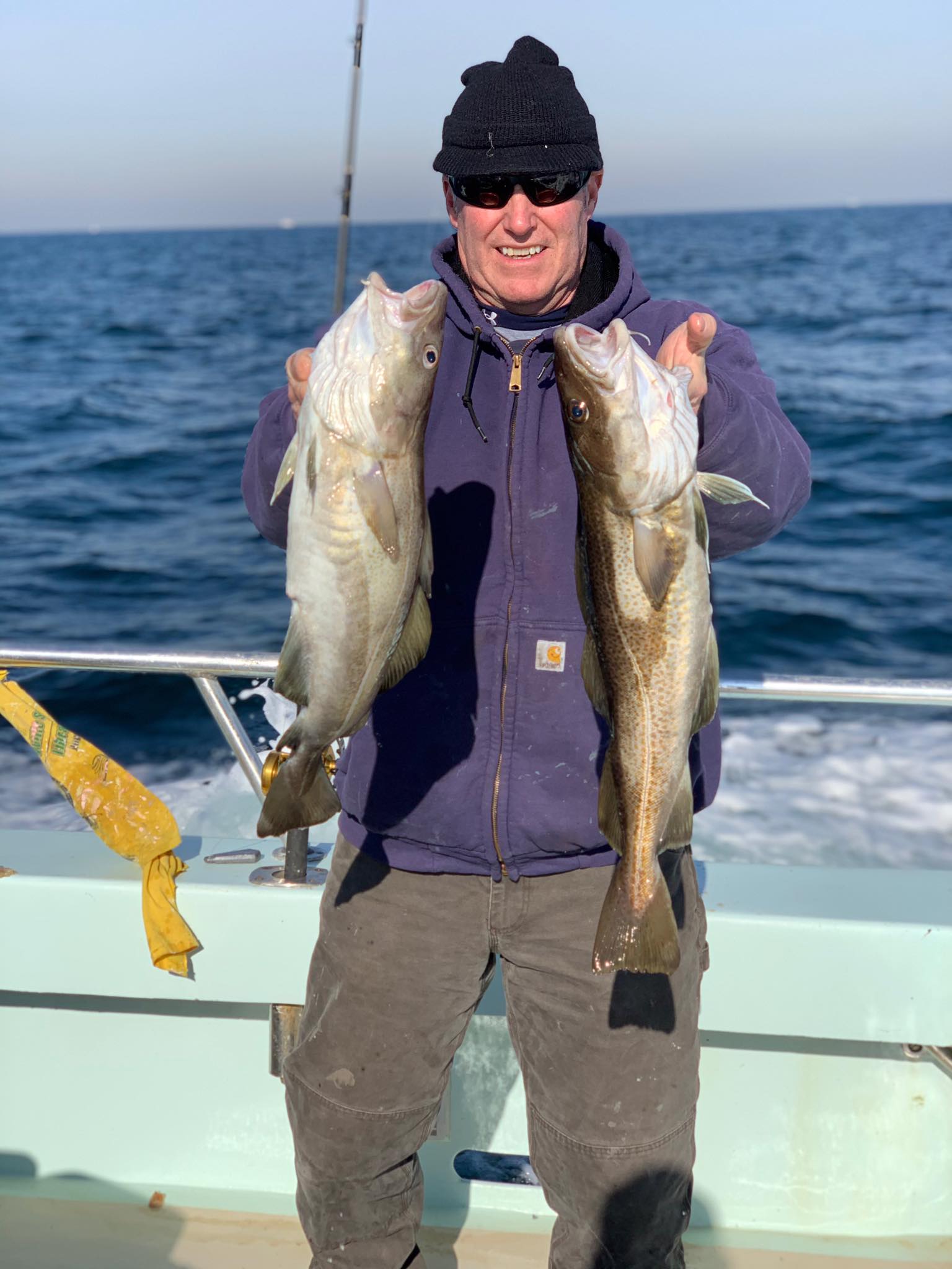 a man holding a fish on a boat in a body of water