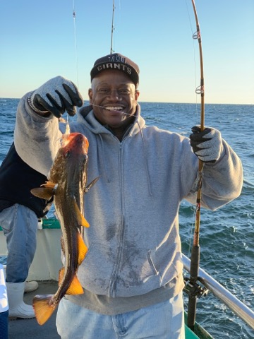 a man holding a fish on a boat in a body of water