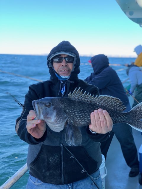 a man holding a fish on a boat in a body of water