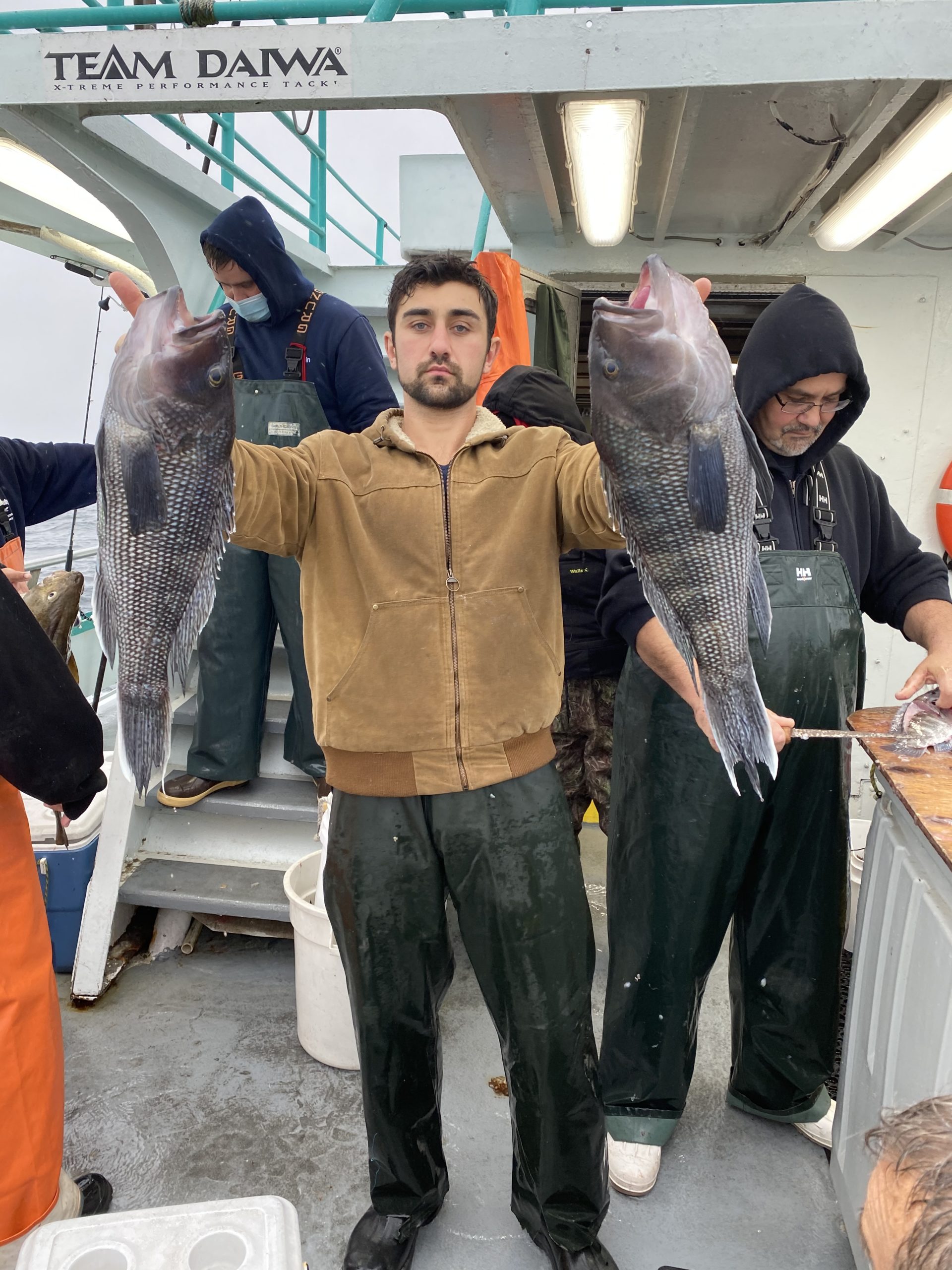 a group of people standing next to a man holding a fish