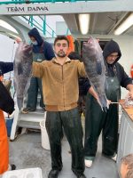 a group of people standing next to a man holding a fish