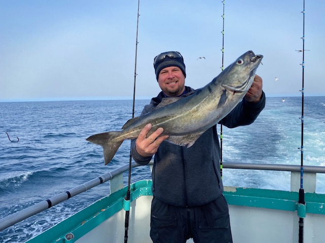 a man holding a fish on a boat in a body of water