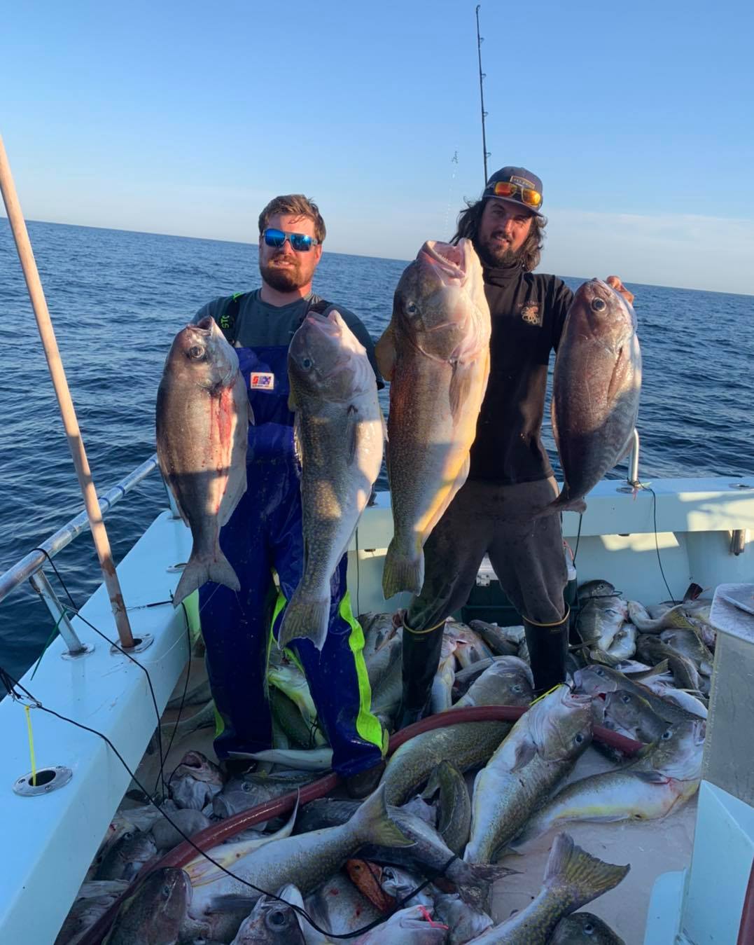 a man holding a fish on a boat in a body of water