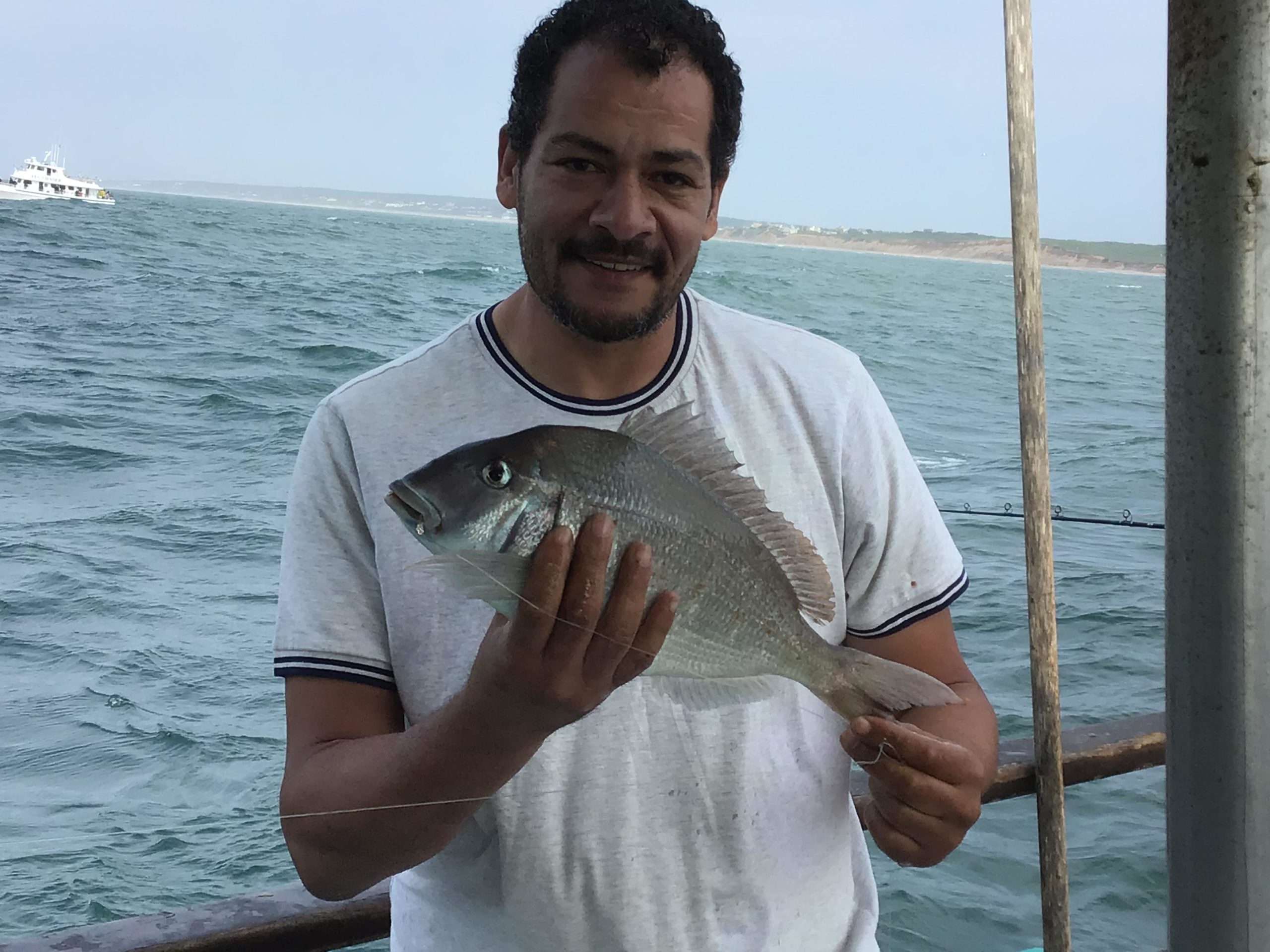 a man holding a fish on a boat in a body of water