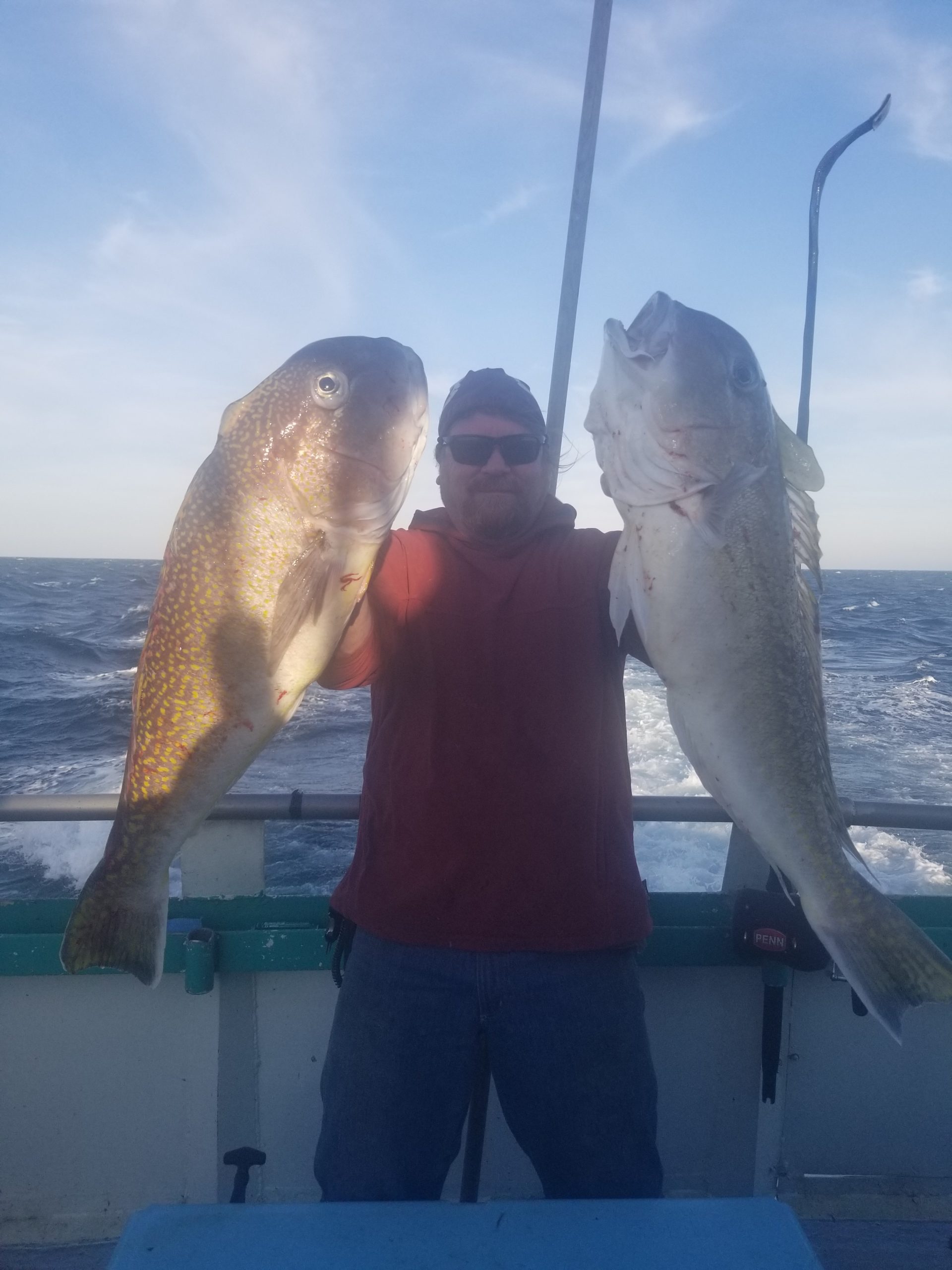 a man holding a fish in front of a body of water