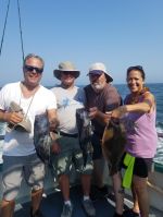 a group of people standing next to a man holding a fish