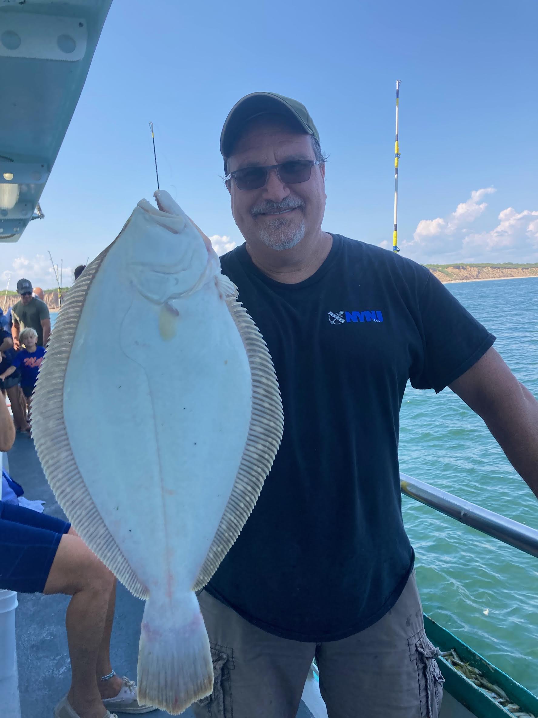 a man holding a fish on a boat in a body of water