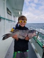 a young boy holding a fish in the water