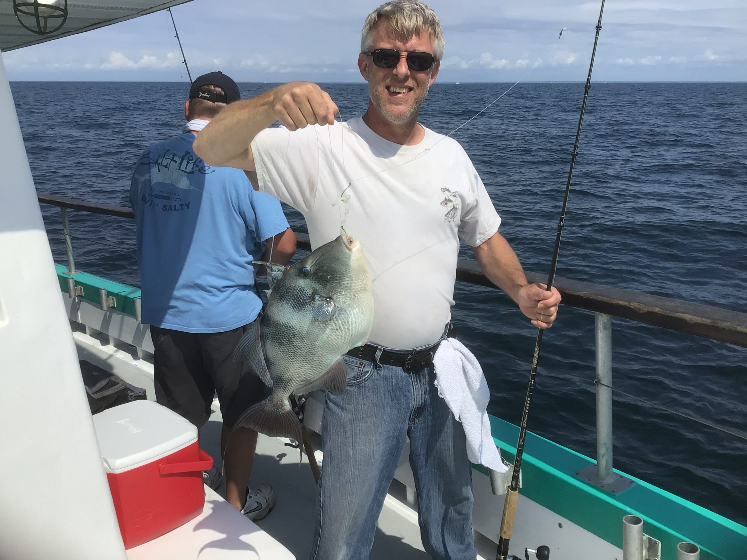 a man holding a fish on a boat in the water