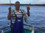 Varavara Rao holding a fish on a boat in a body of water