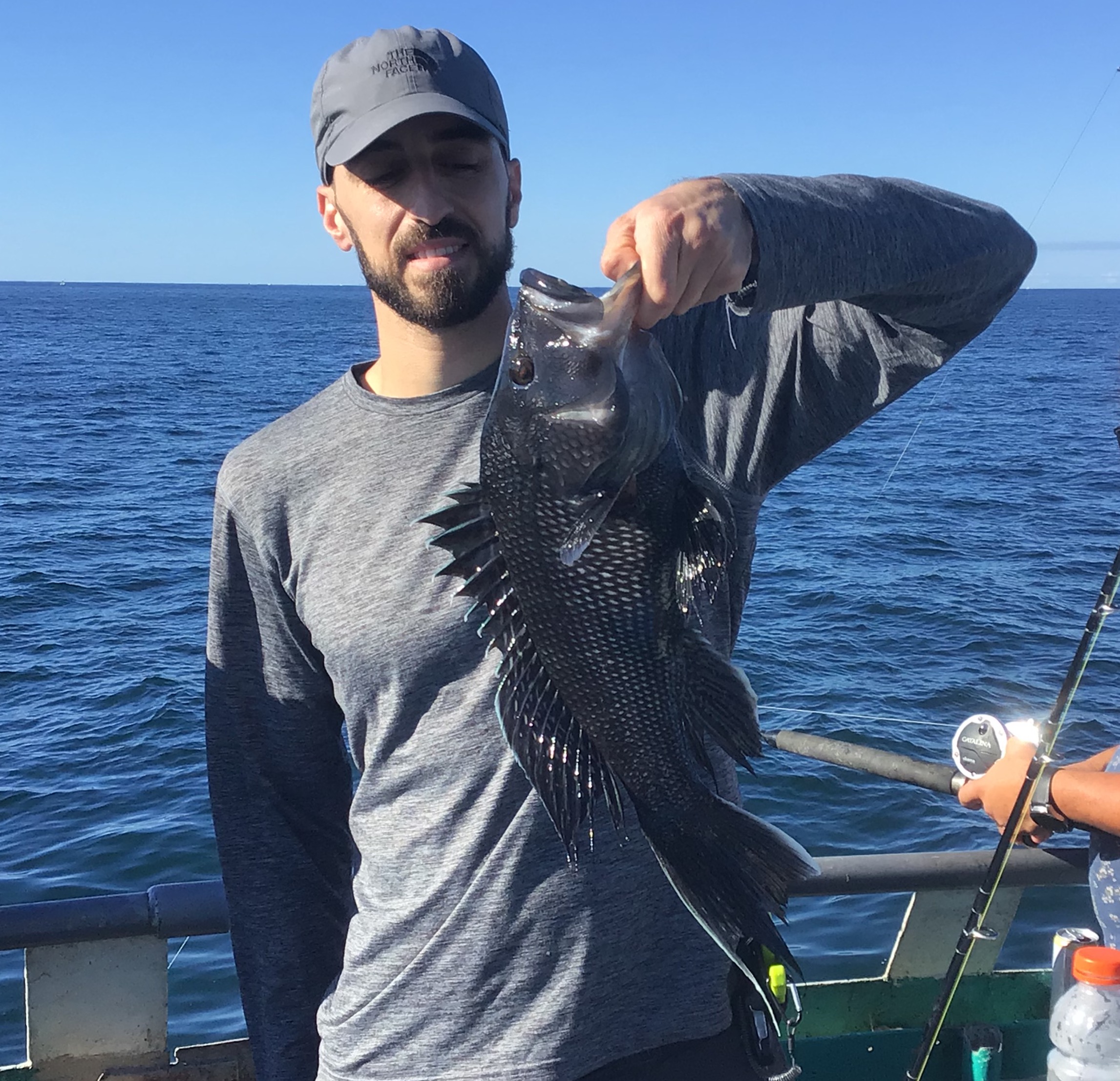 a man holding a fish on a boat in a body of water
