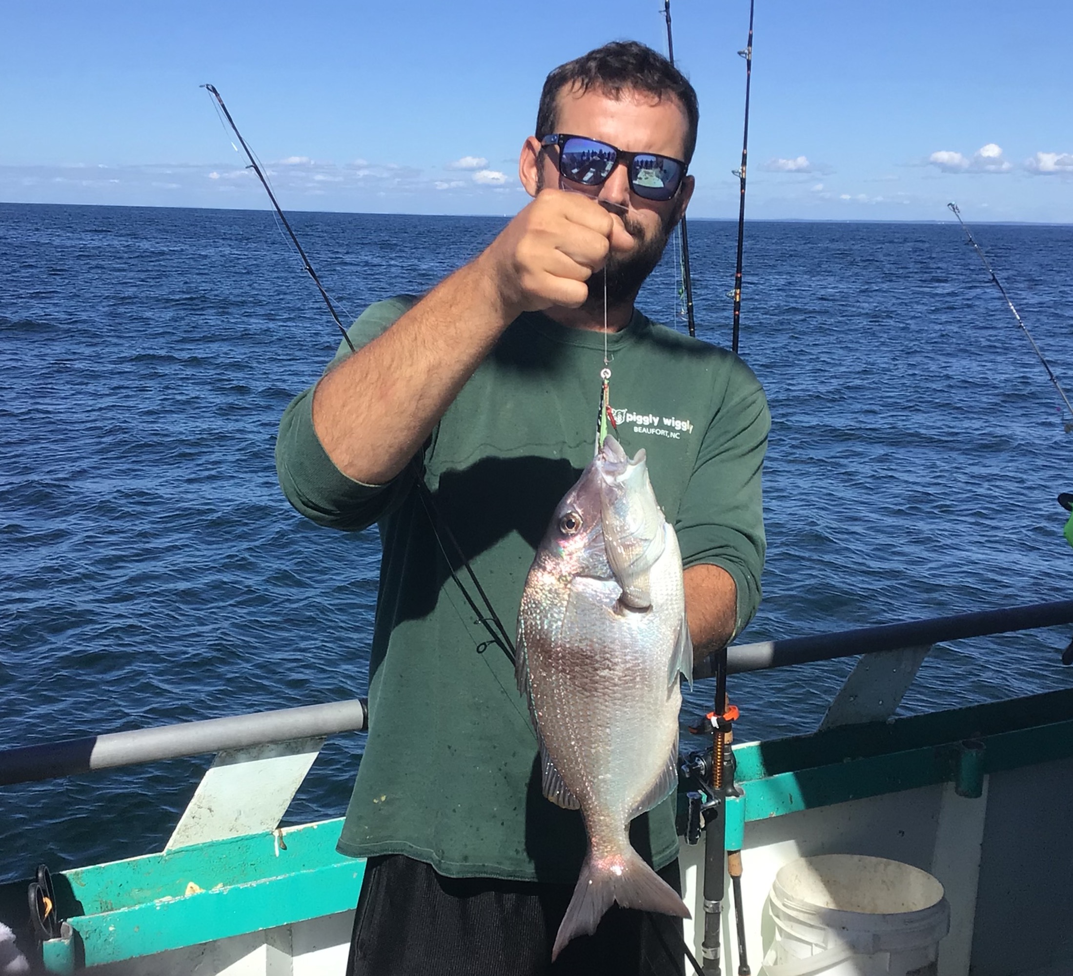 a man holding a fish on a boat in a body of water