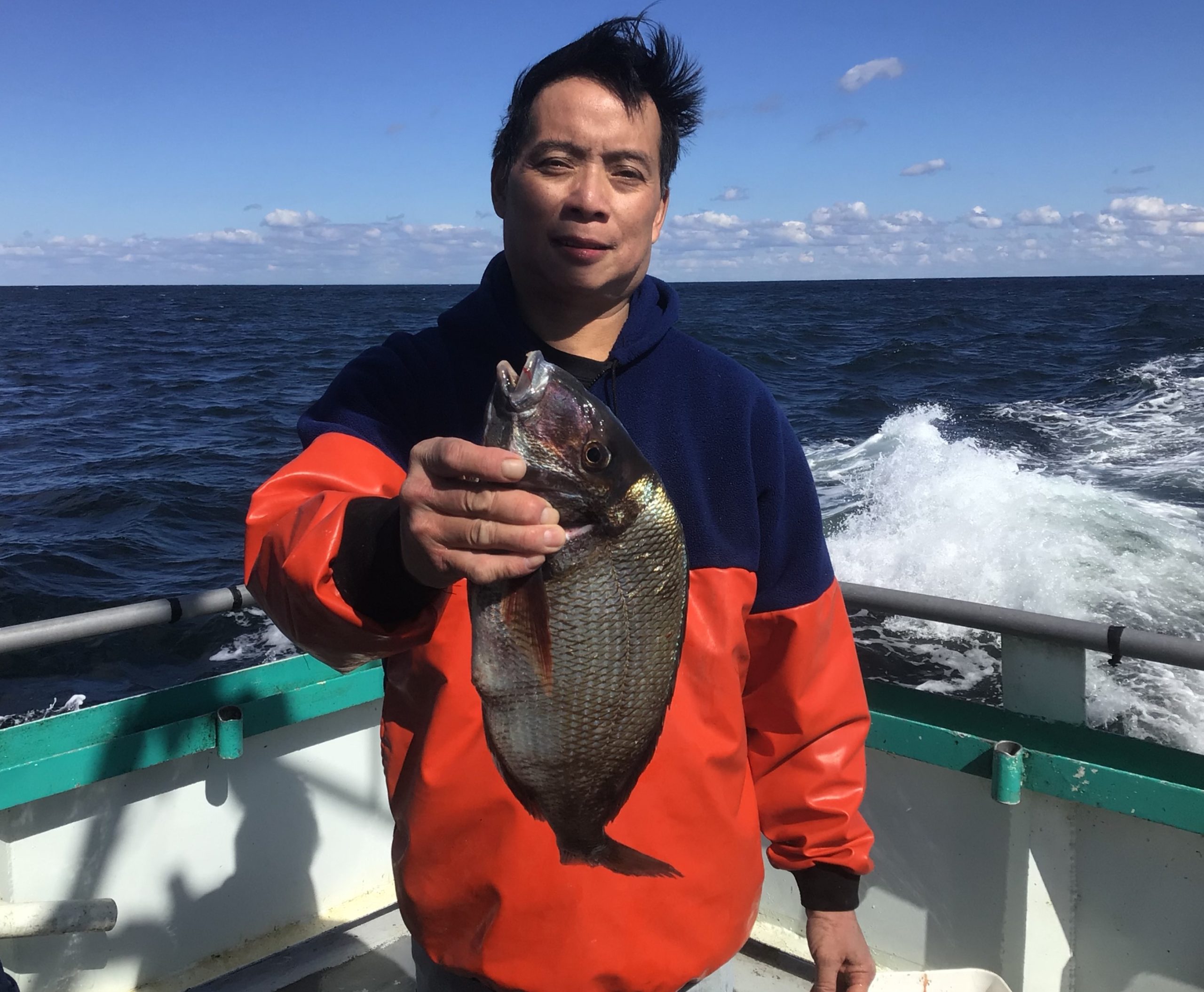 a man holding a fish in front of a body of water