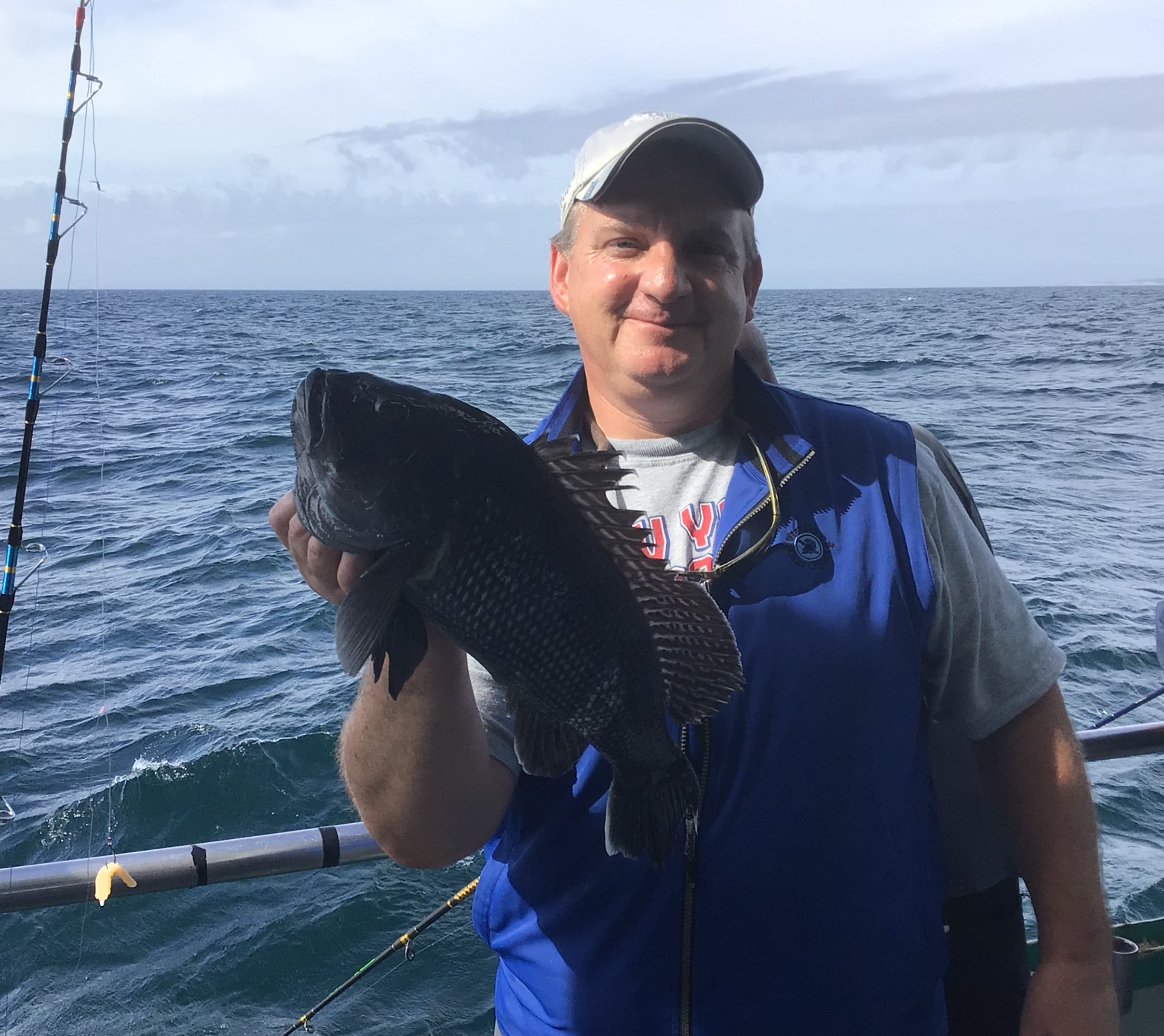a man holding a fish on a boat in a body of water