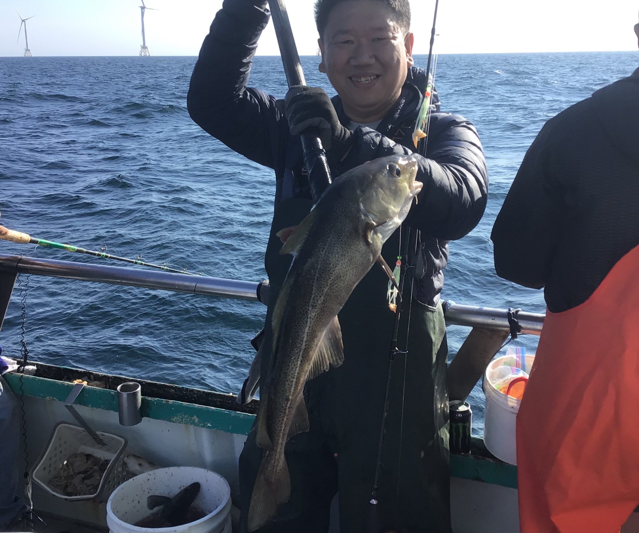 Steven Chang holding a fish on a boat in a body of water