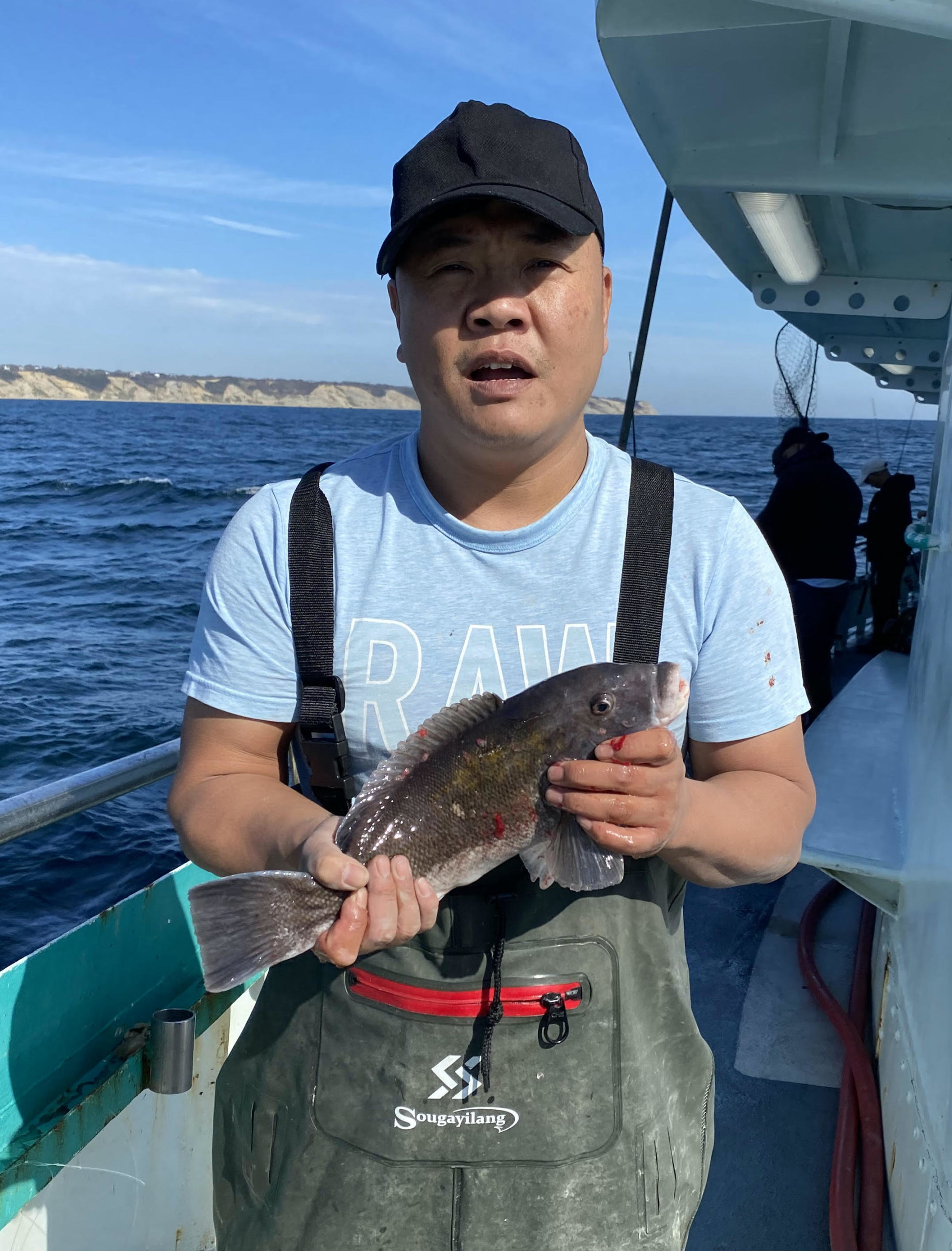 a man holding a fish on a boat