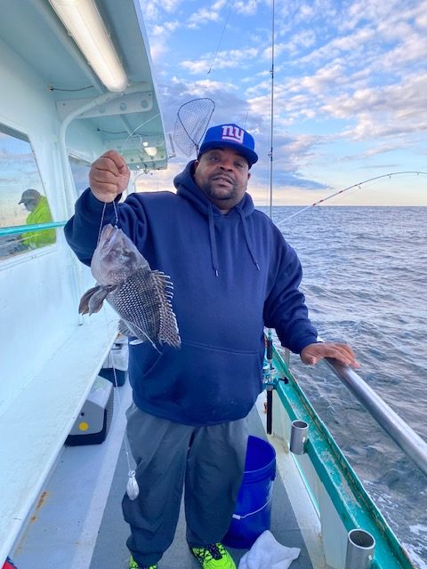 a man holding a fish on a boat posing for the camera