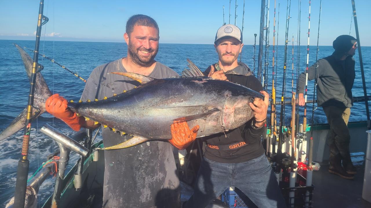 a man holding a fish on a boat in the water