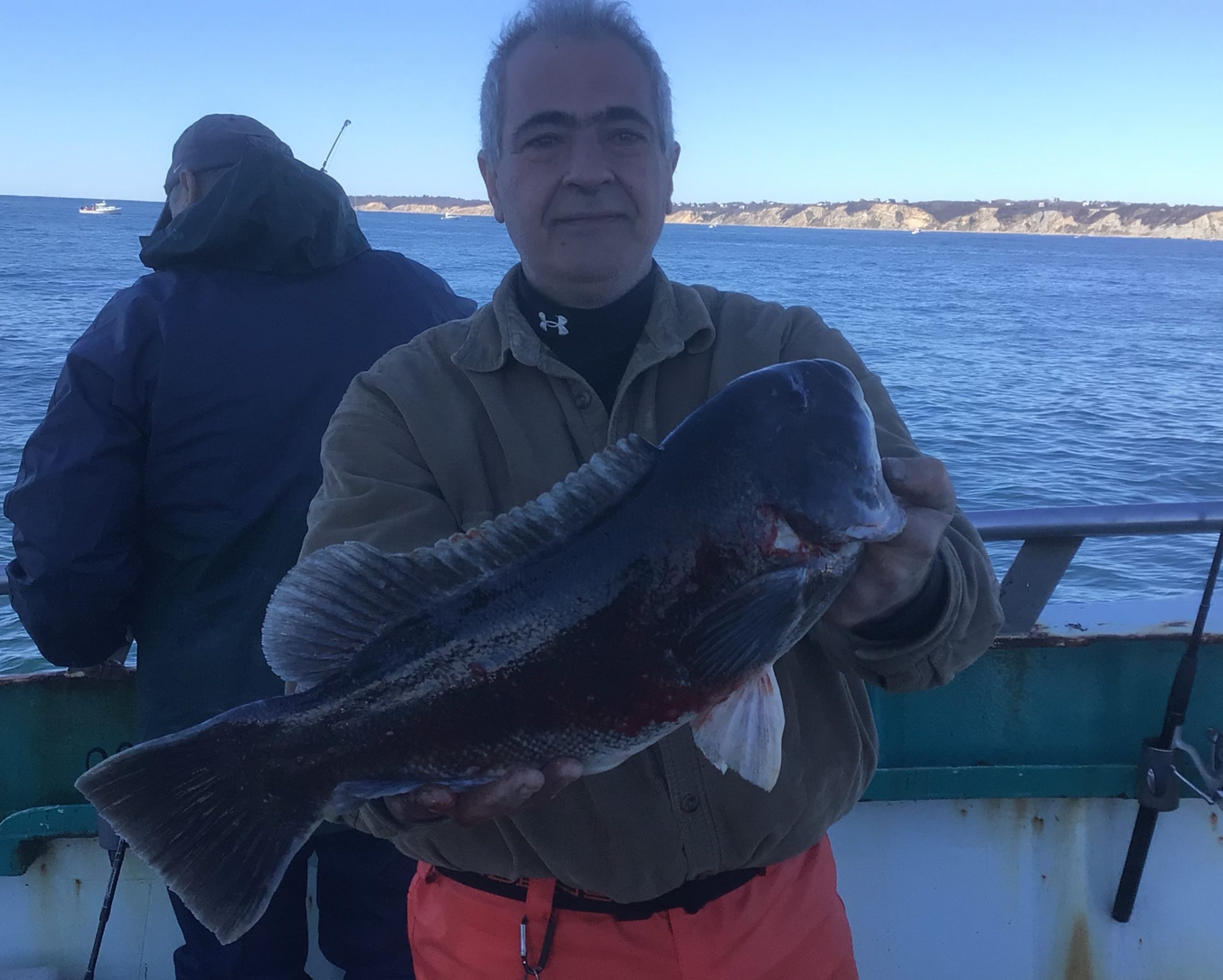 a man holding a fish on a boat in a body of water