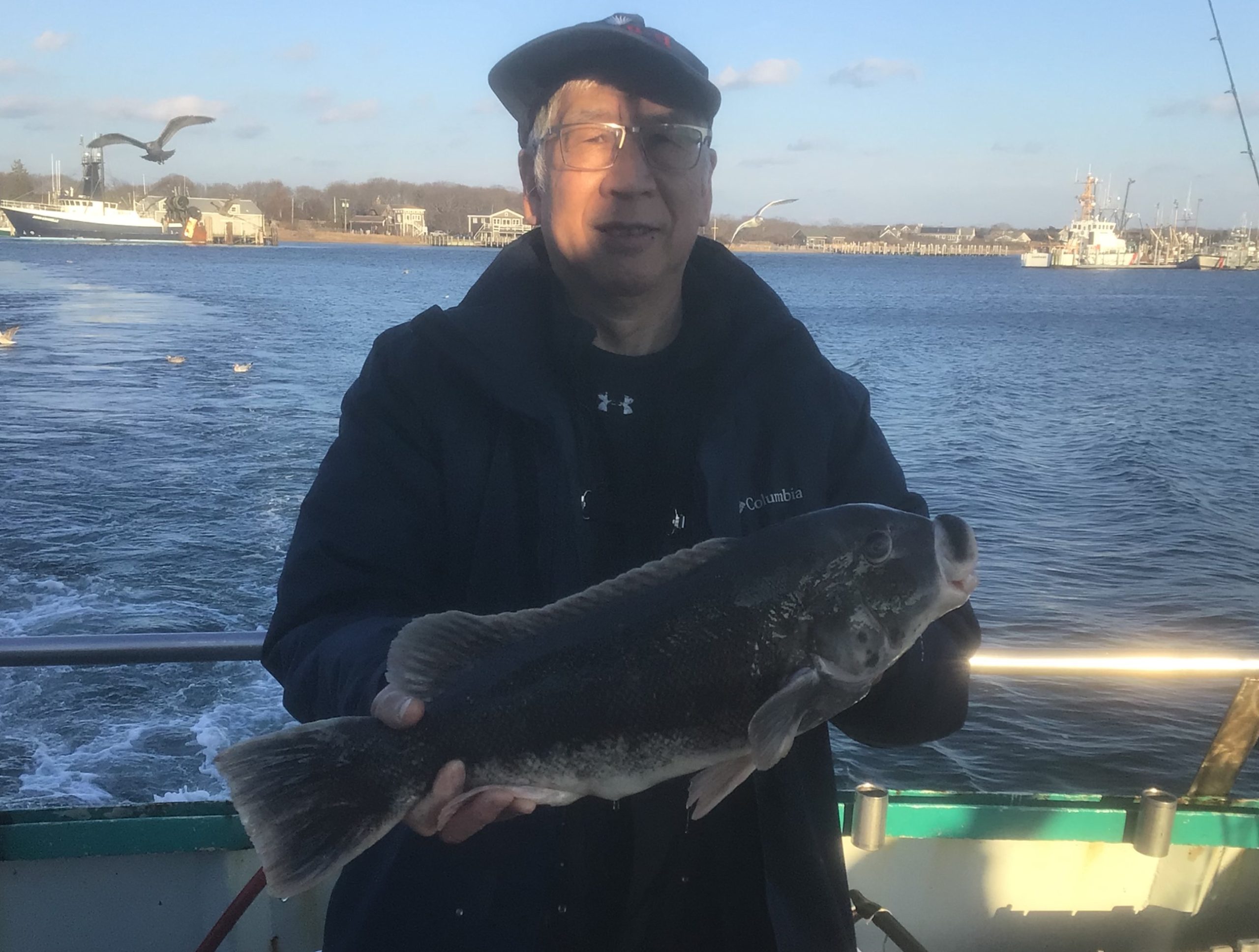a man holding a fish on a boat in a body of water