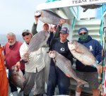 a group of people standing in front of a military man holding a fish