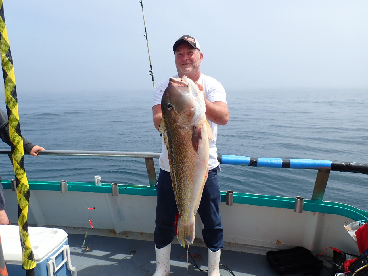 a man holding a fish on a boat in the water