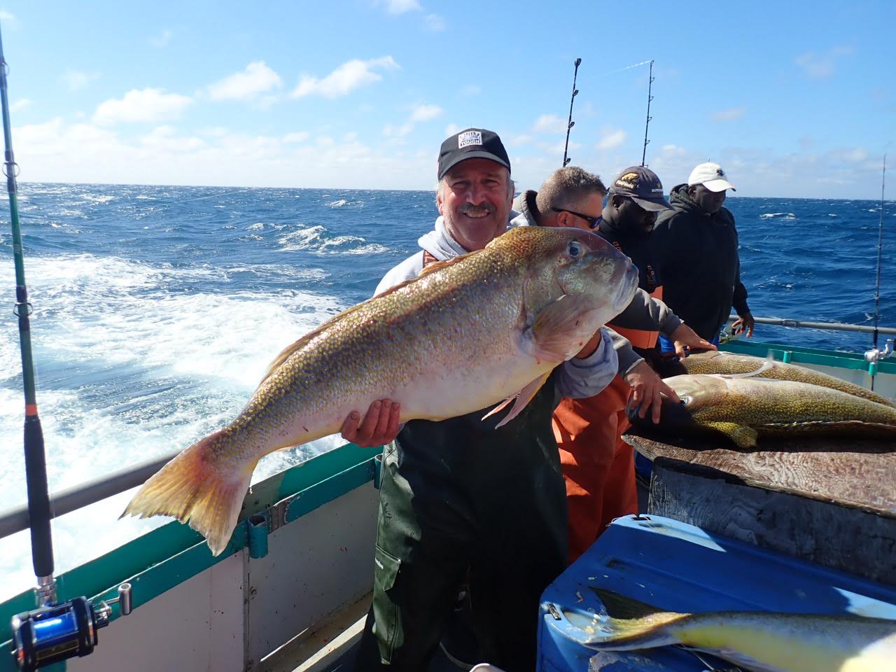a person holding a fish on a boat in a body of water
