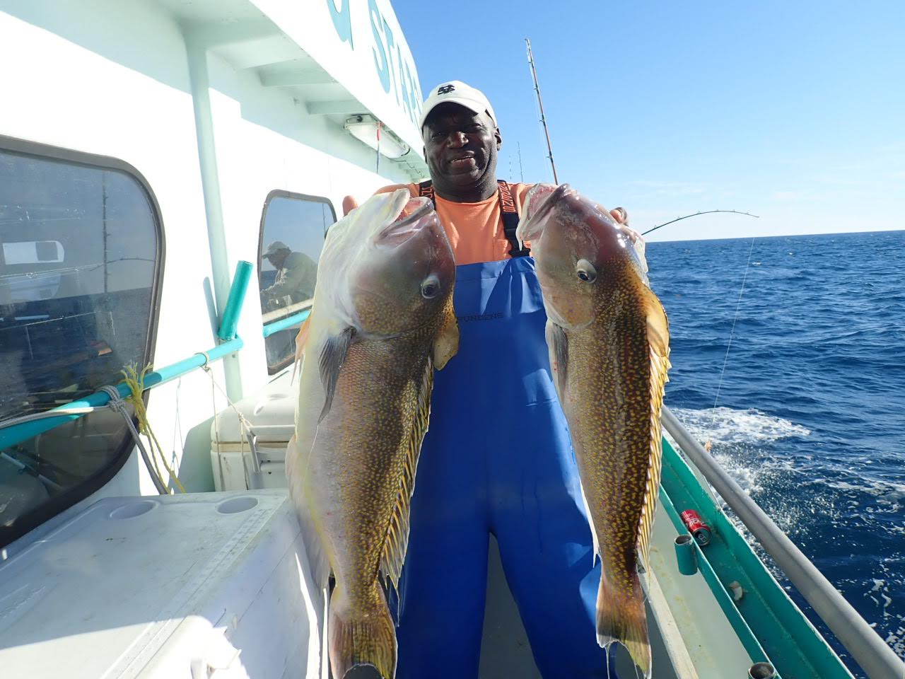 a person holding a fish on a boat posing for the camera