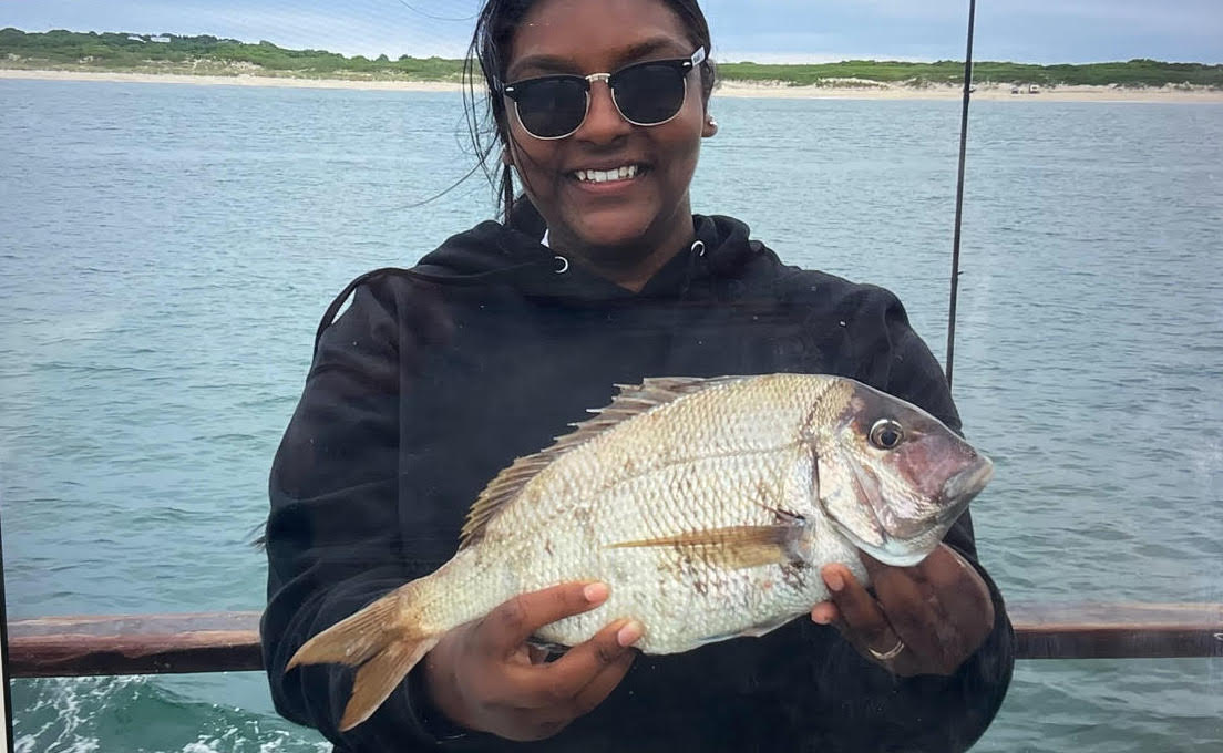 a person holding a fish on a boat in a body of water