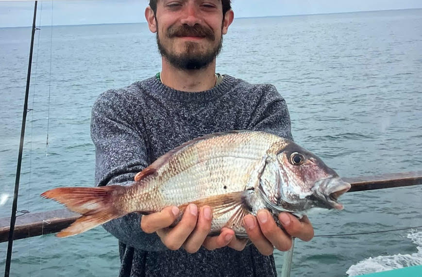 a man holding a fish on a boat in a body of water
