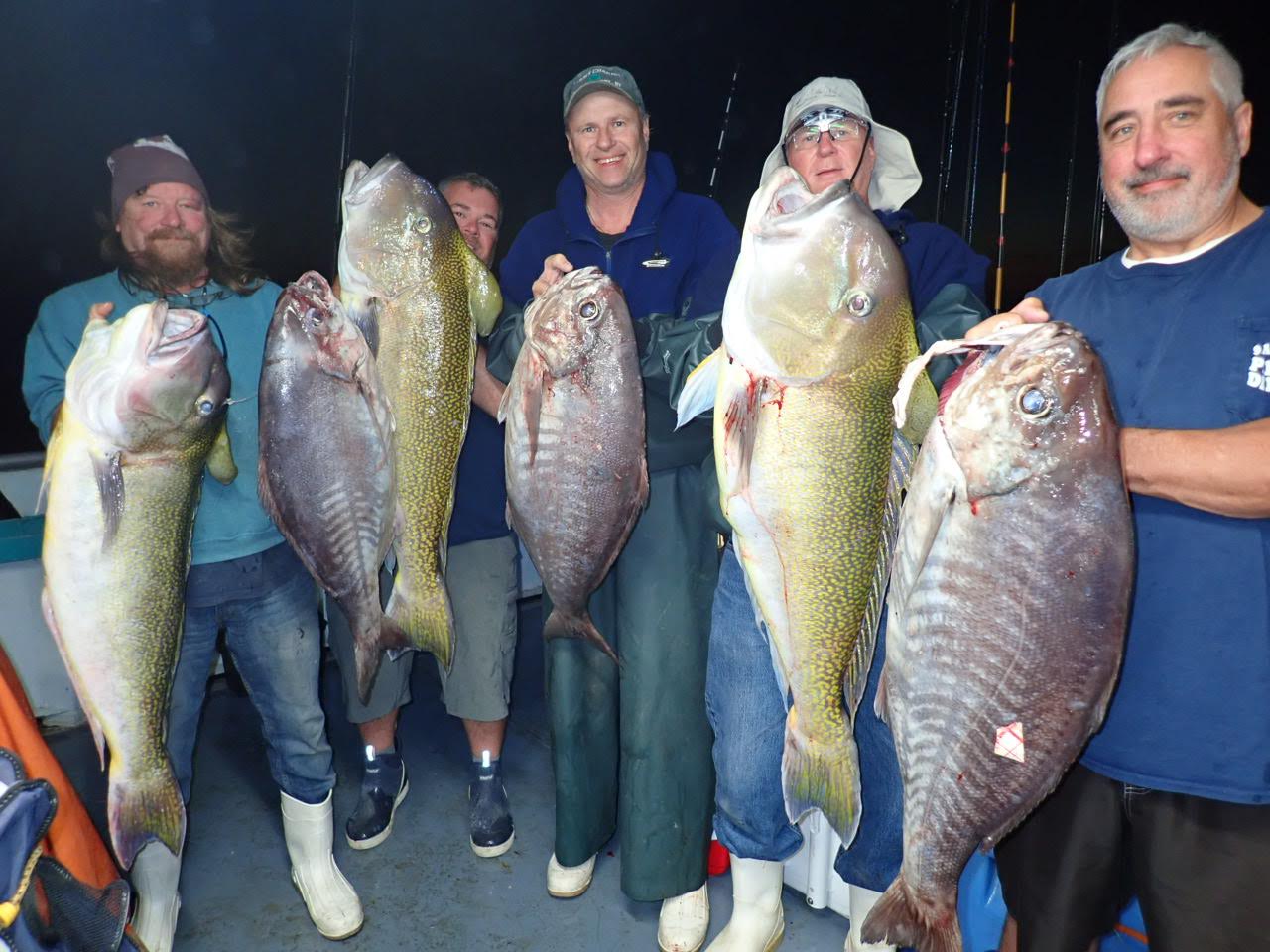 a group of people posing for a photo in front of a fish