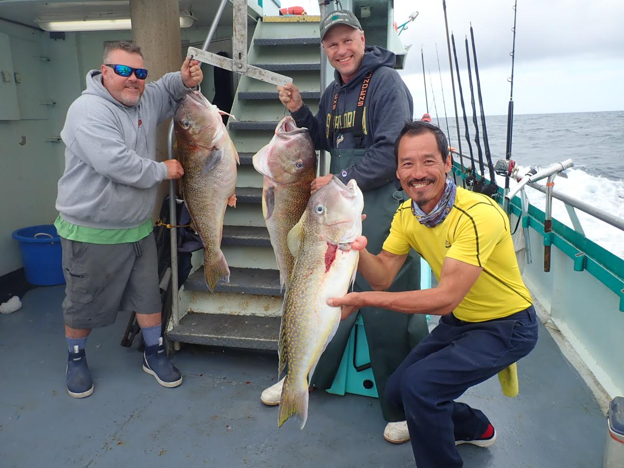 a group of people standing next to a man holding a fish