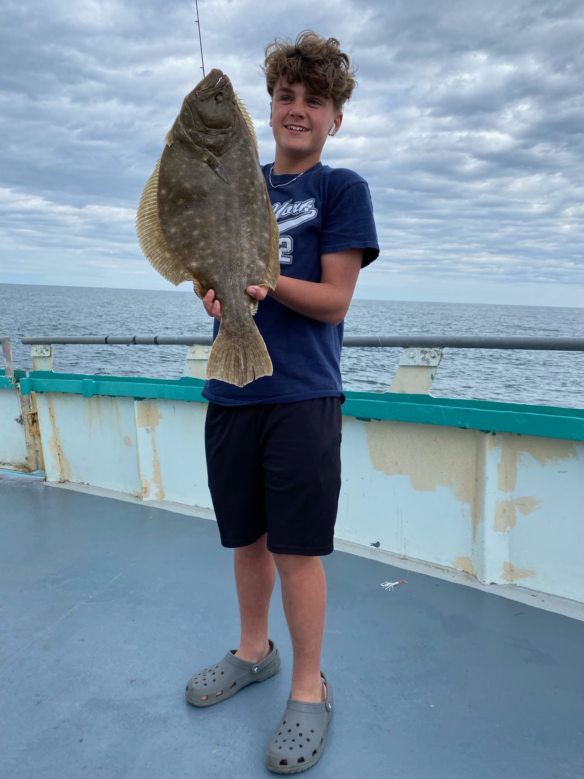 a man holding a fish in front of a body of water