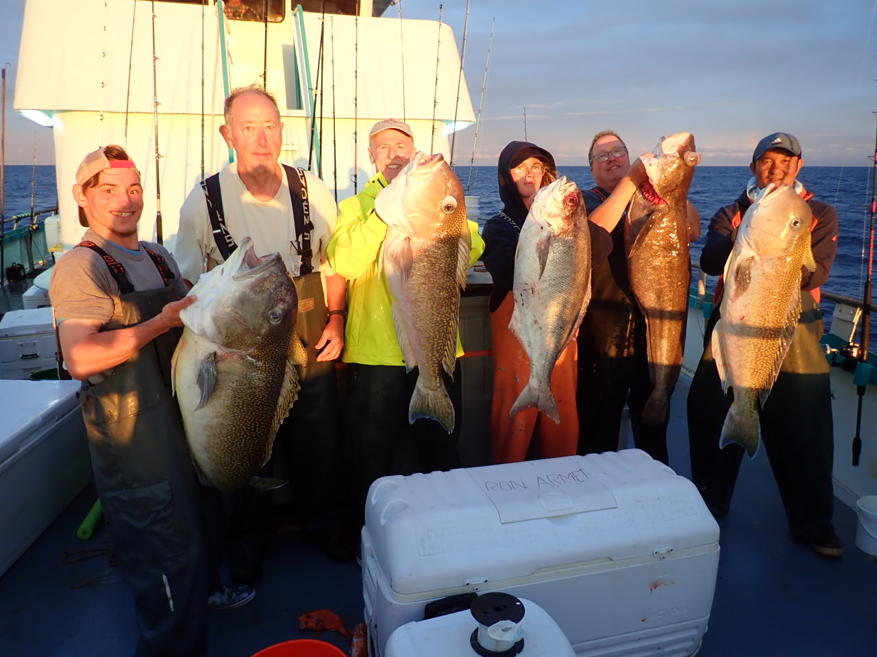 a group of people standing next to a person holding a fish