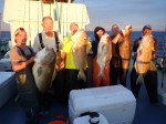 a group of people standing next to a person holding a fish