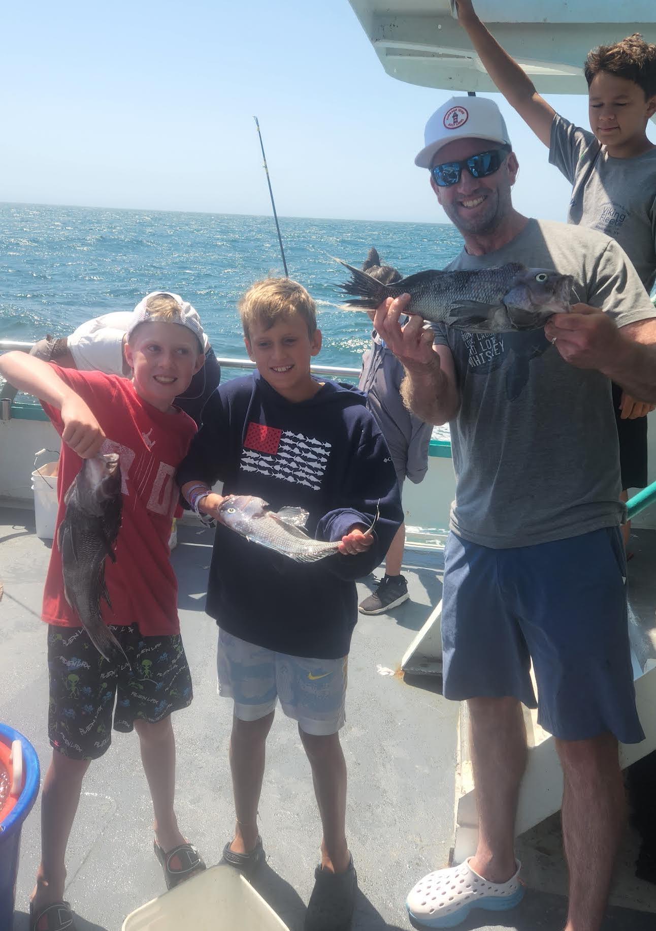 a group of people standing next to a man holding a fish