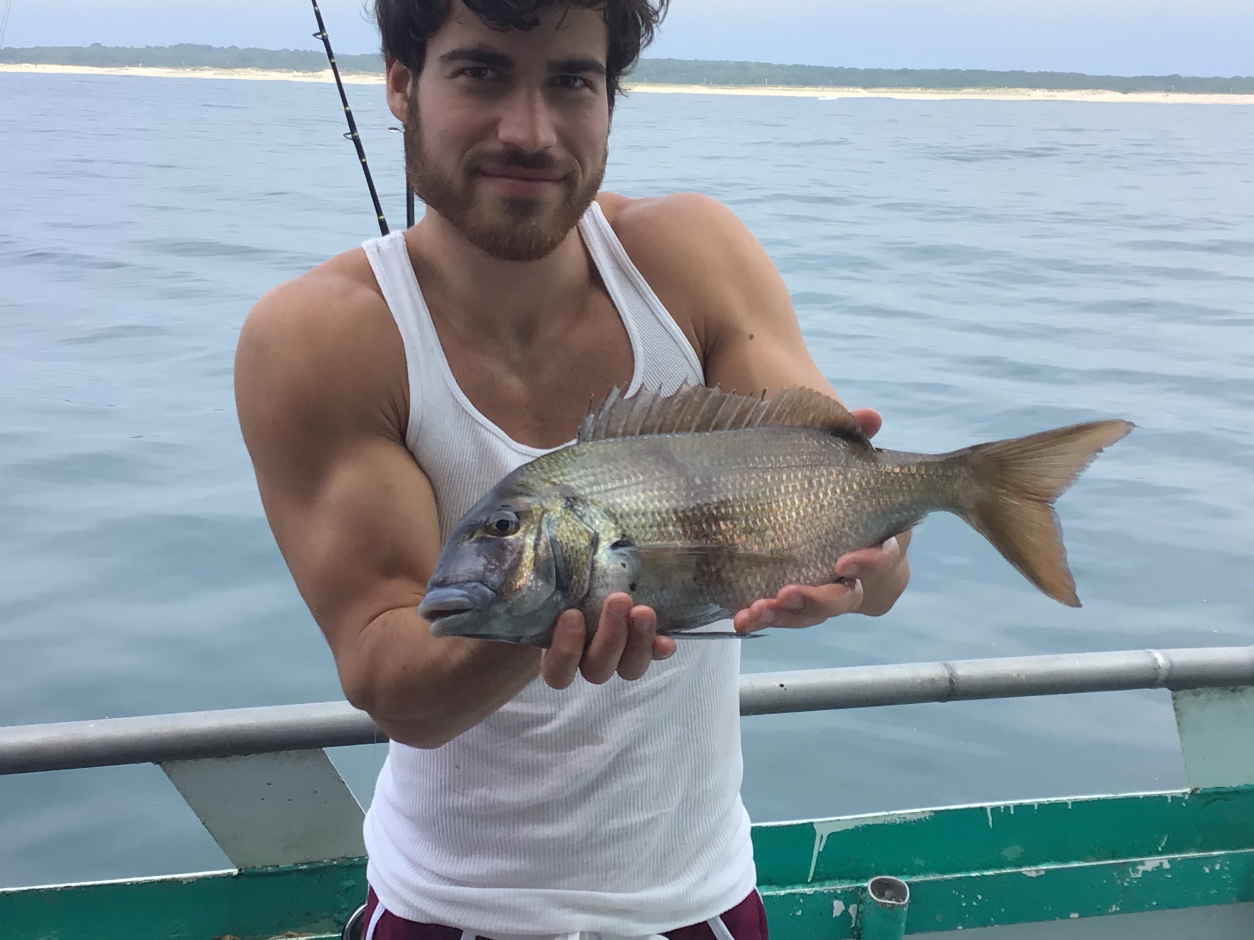 a person holding a fish on a boat in a body of water