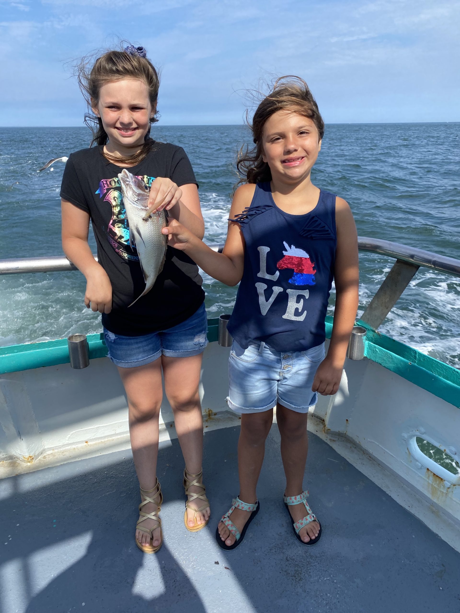 a little girl standing next to a body of water
