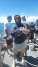 a group of people standing next to a person holding a fish