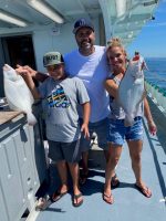 a group of people standing next to a person holding a fish