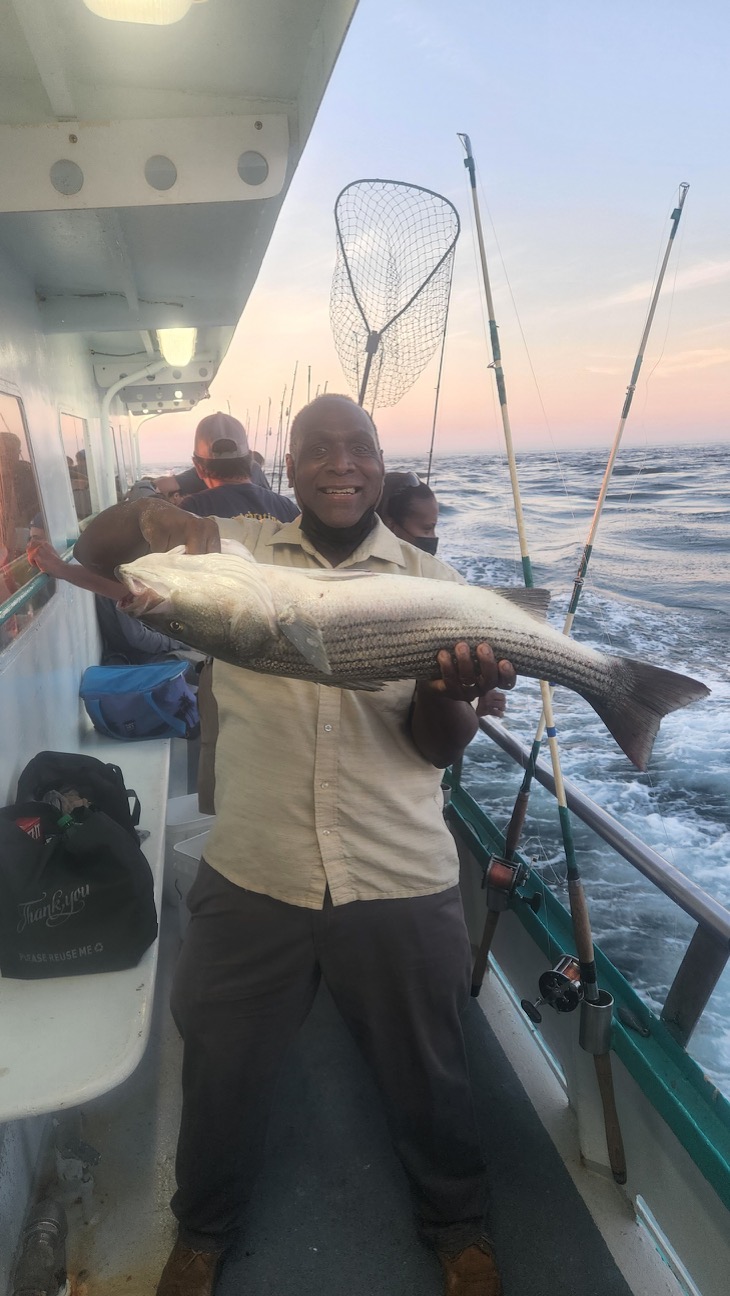 Olara Otunnu holding a fish on a boat