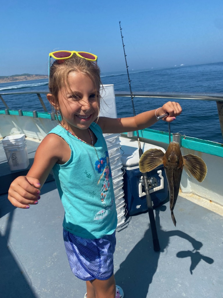 a little girl standing next to a body of water
