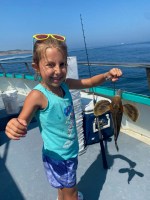 a little girl standing next to a body of water