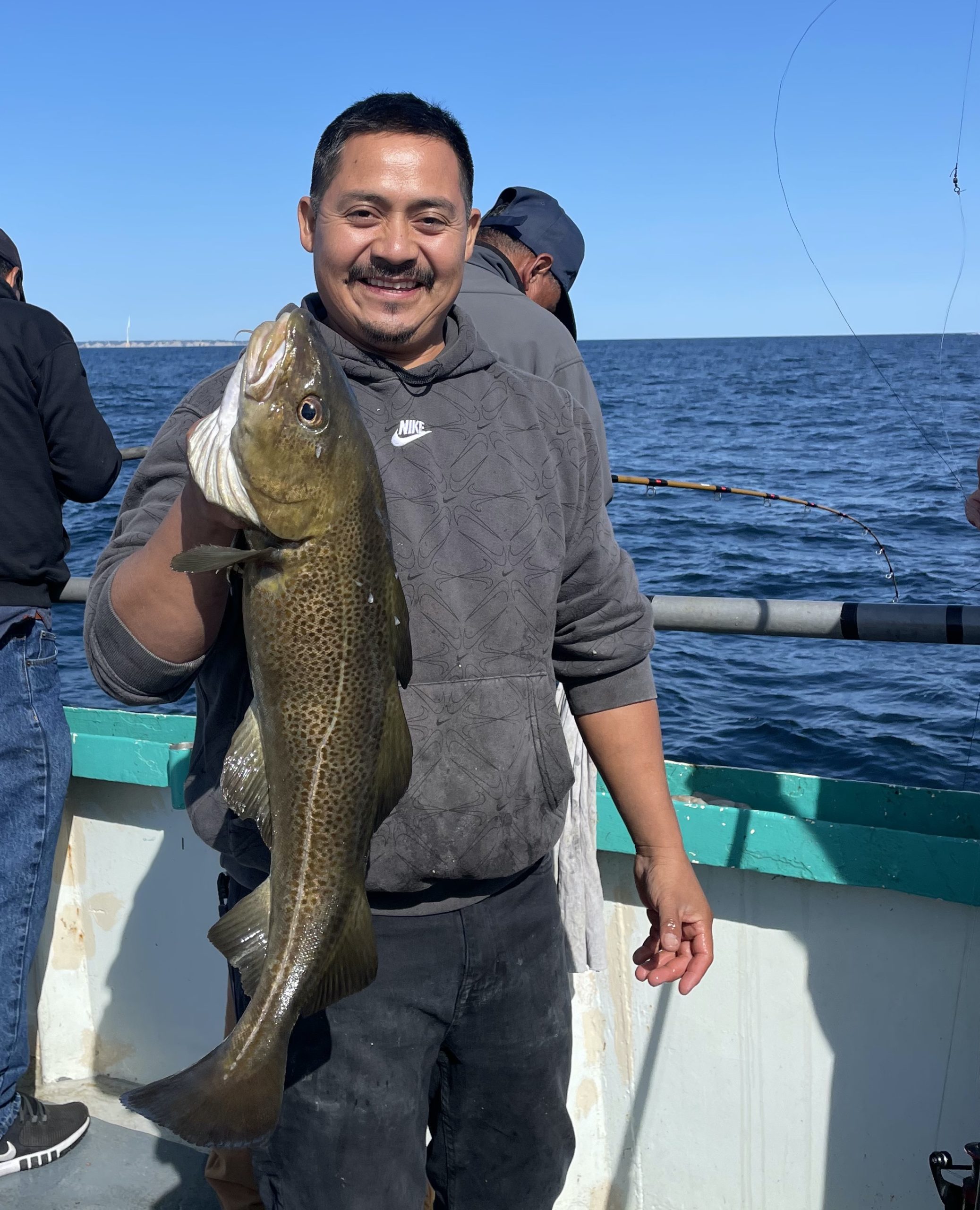 a man holding a fish on a boat in a body of water