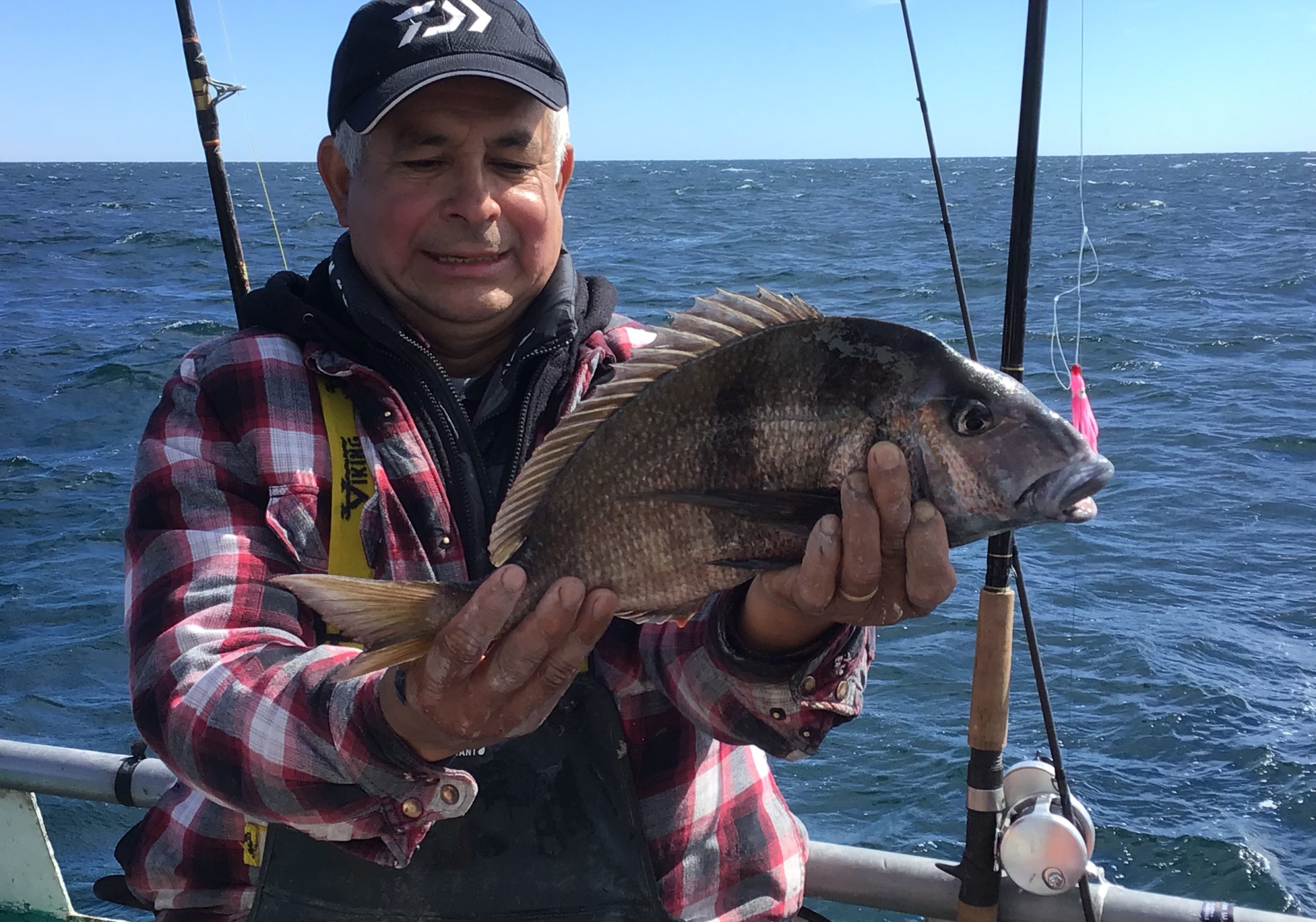 a man holding a fish on a boat in a body of water