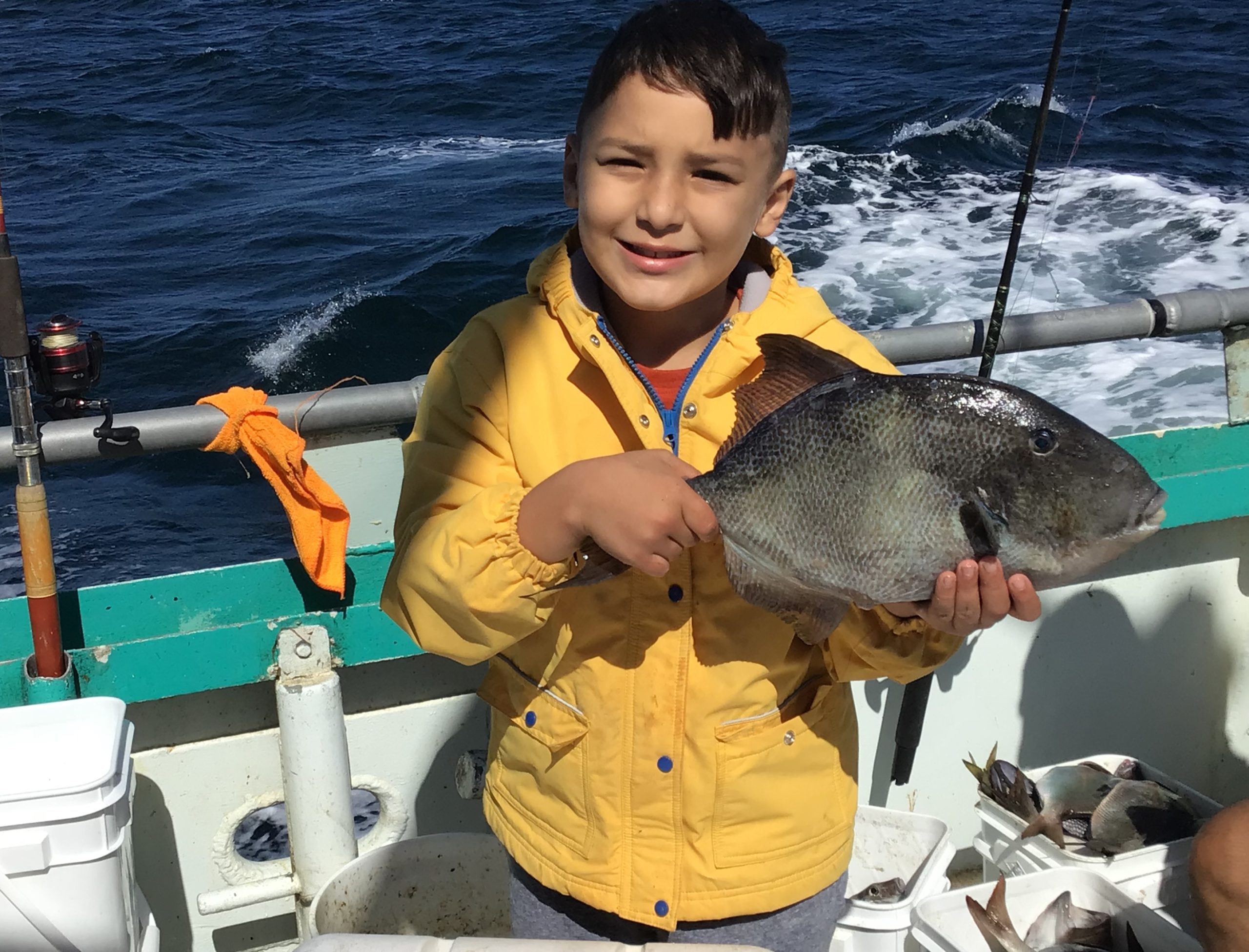 a young boy holding a fish on a boat in the water