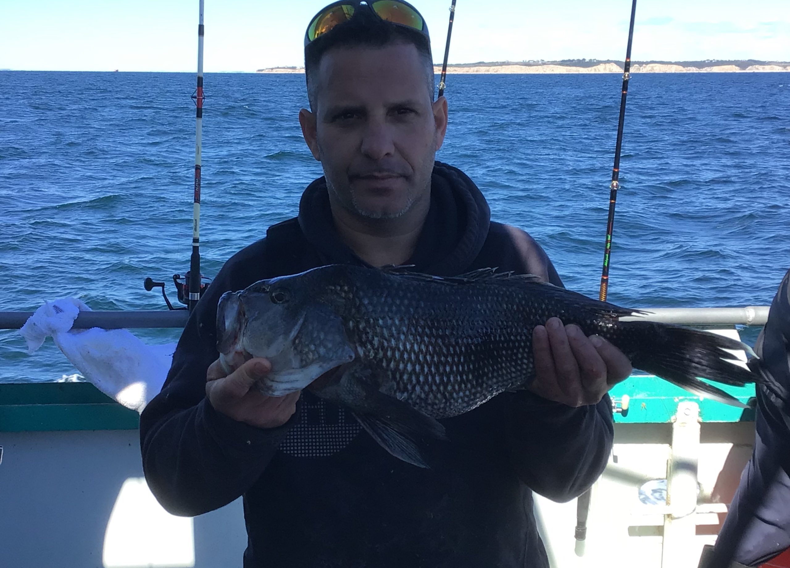 a man holding a fish on a boat in a body of water