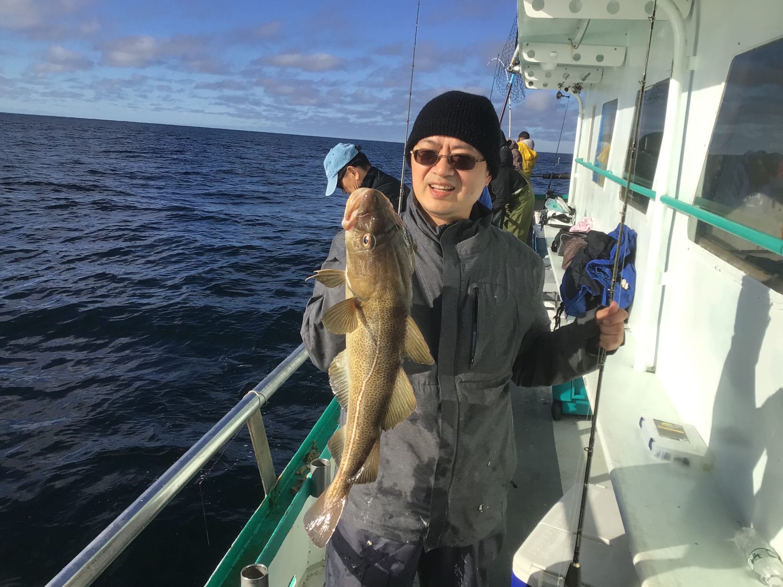 a man holding a fish on a boat posing for the camera