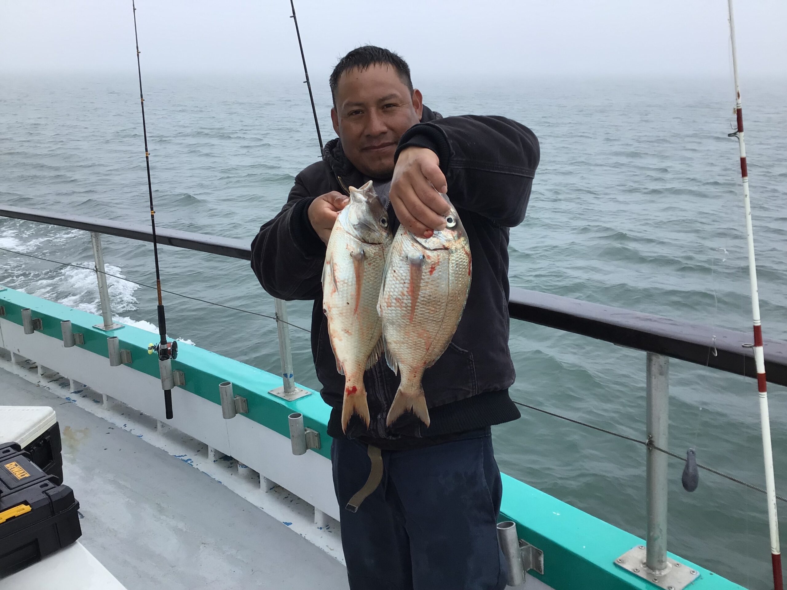 a man holding a fish on a boat in a body of water