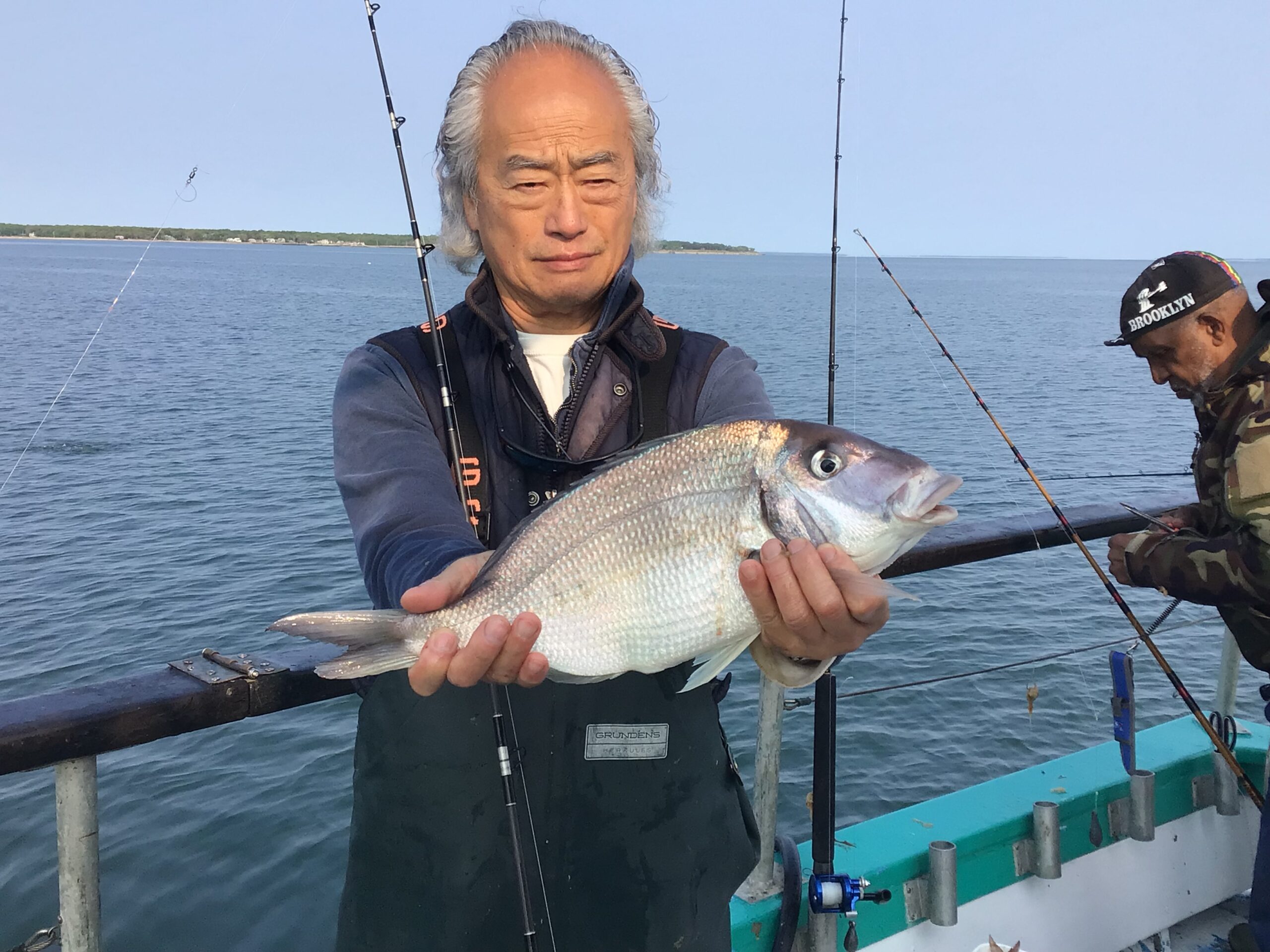Li Bomin holding a fish on a boat in a body of water